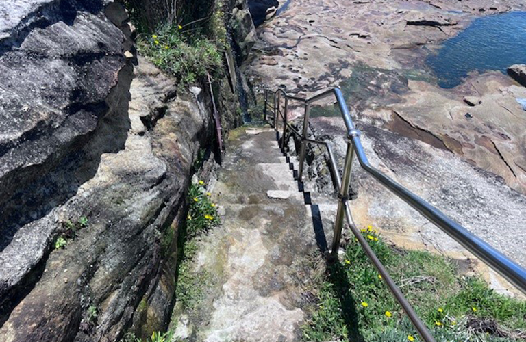 An image of concrete steps leading to a rockpool.