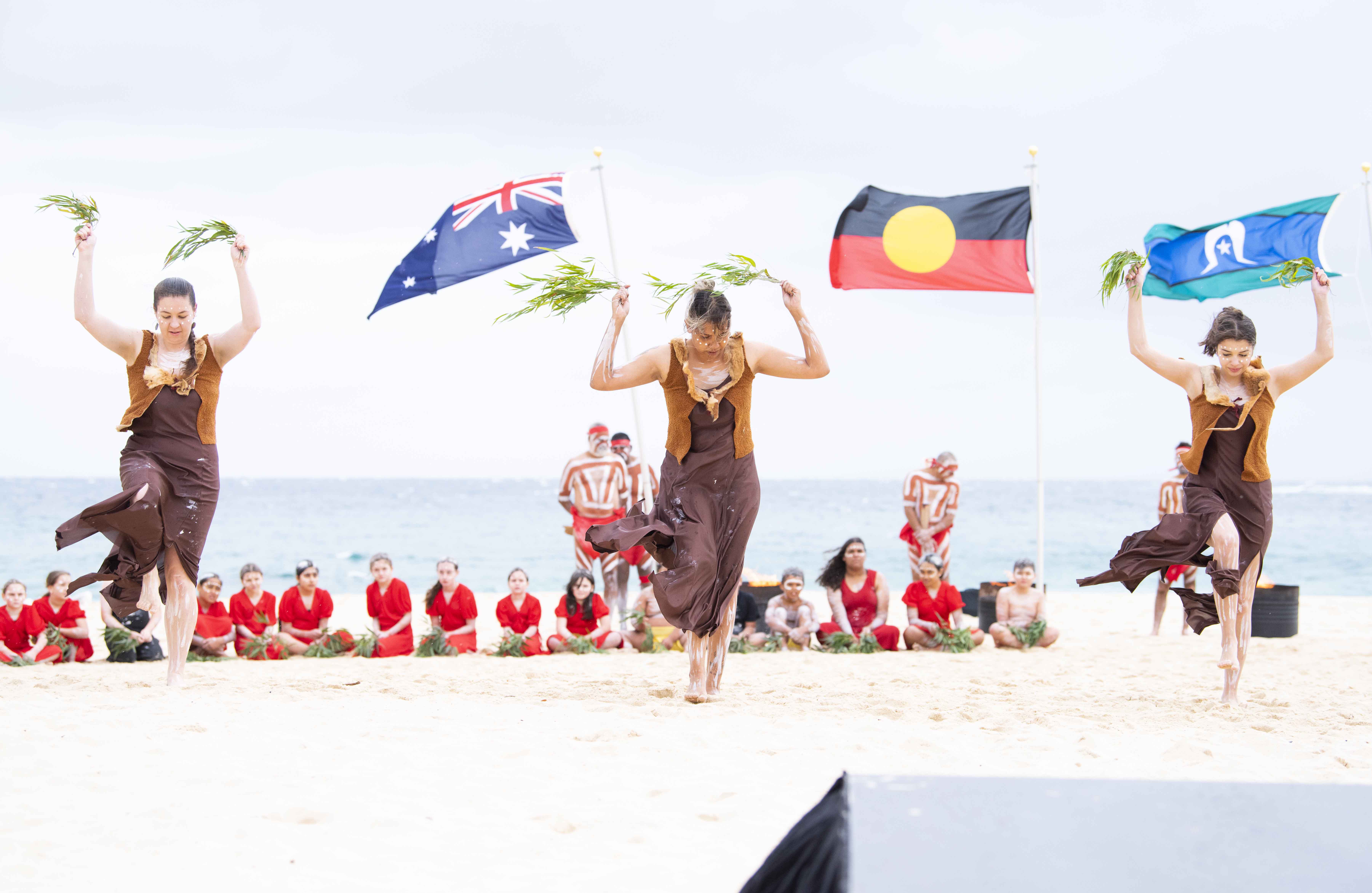 Three Aboriginal dancers perform on Coogee Beach in Sydney.